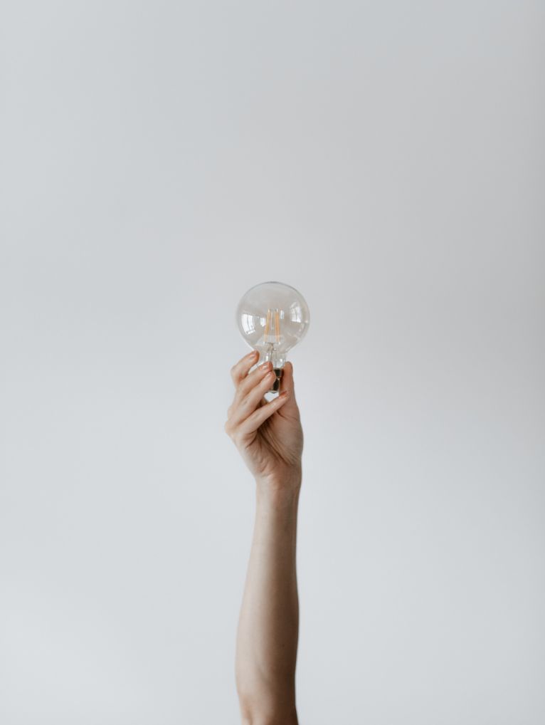 photo représentant une main tendue vers ciel et tenant une ampoule