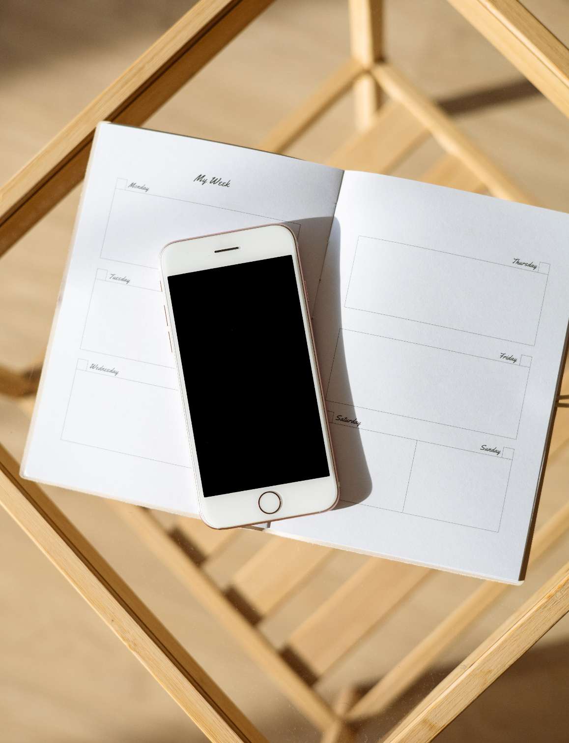 photo représentant un téléphone mobile blanc, posé sur un agenda ouvert, le tout entreposé sur un tabouret en bois ajouré
