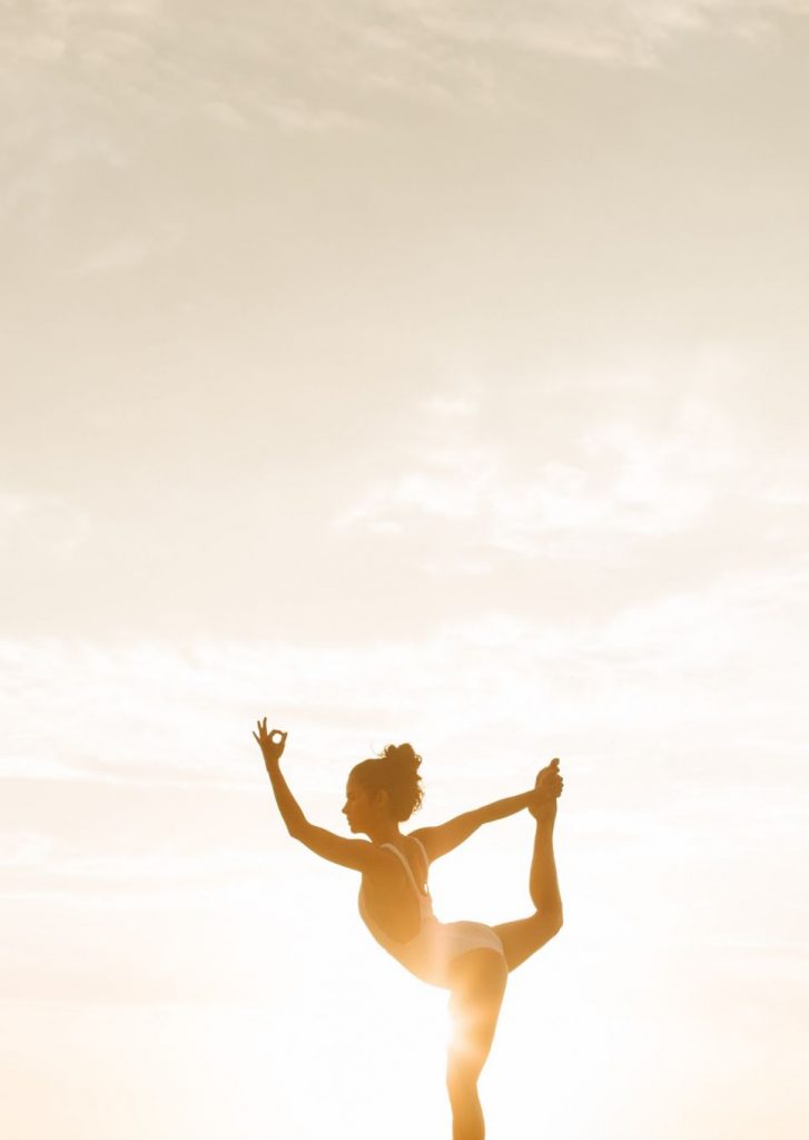 photo représentant une femme zen, en équilibre, avec le soleil levant en arrière plan