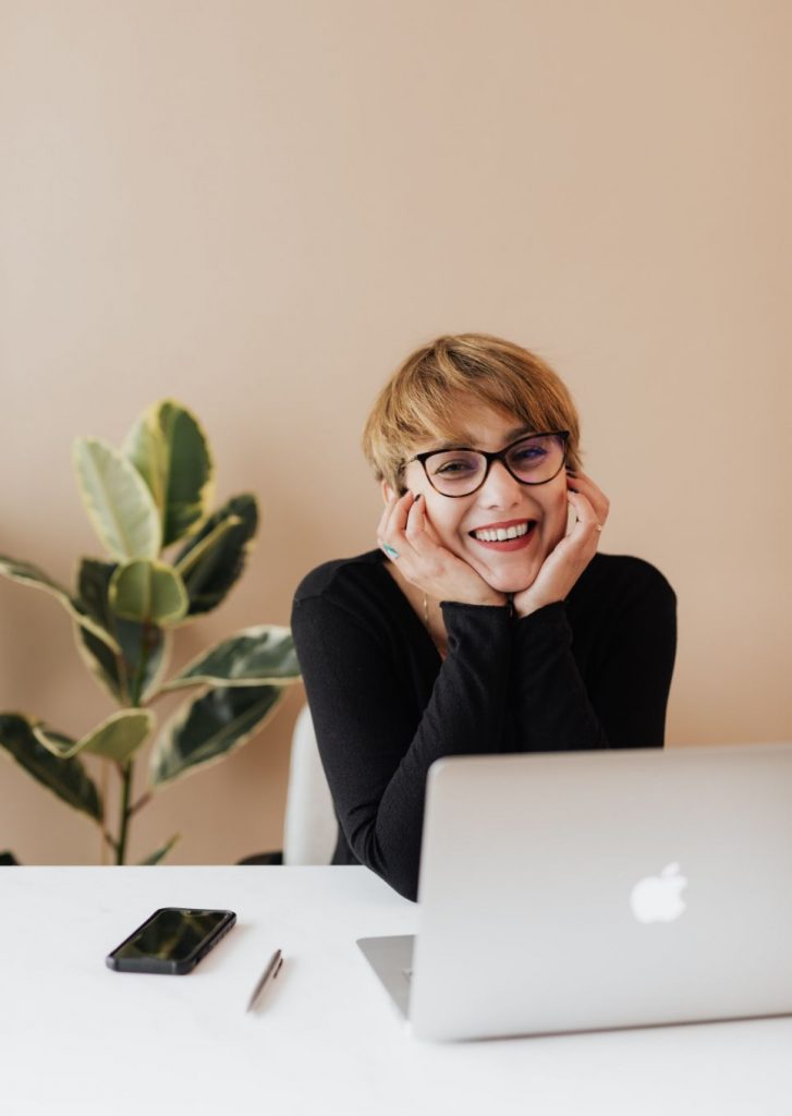 photo représentant une femme souriante devant son écran d'ordinateur
