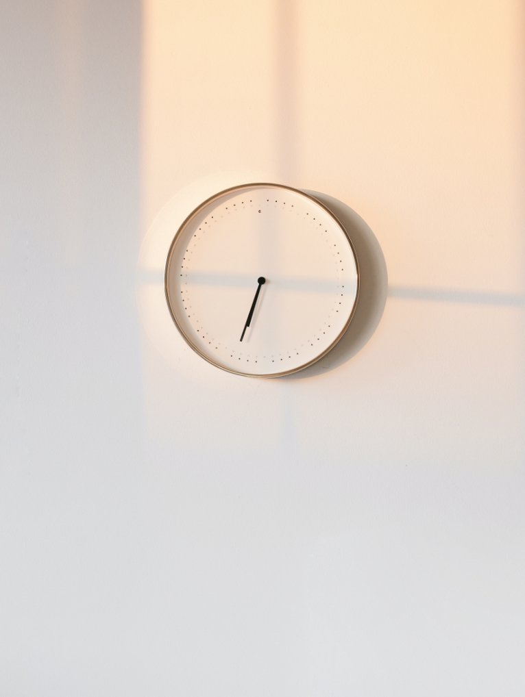 photo représentant une horloge blanche accrochée sur un mur blanc